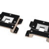 Angled view of two black textured mounting plates with beige edges and a central square cutout, each showing screw holes.